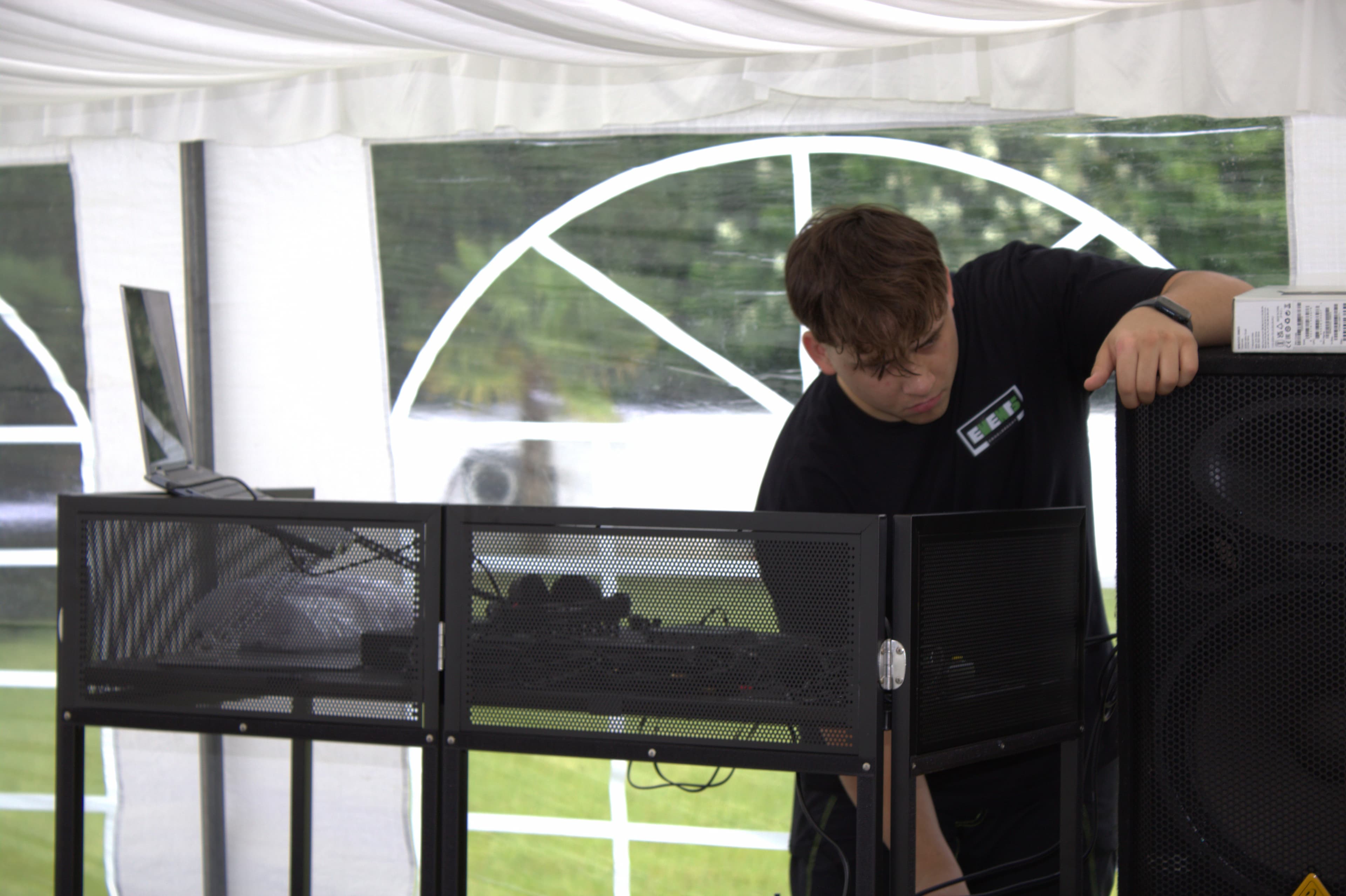 Veranstaltungstechniker beim Aufbau von DJ- und Beschallungstechnik in einem Festzelt für eine Veranstaltung.