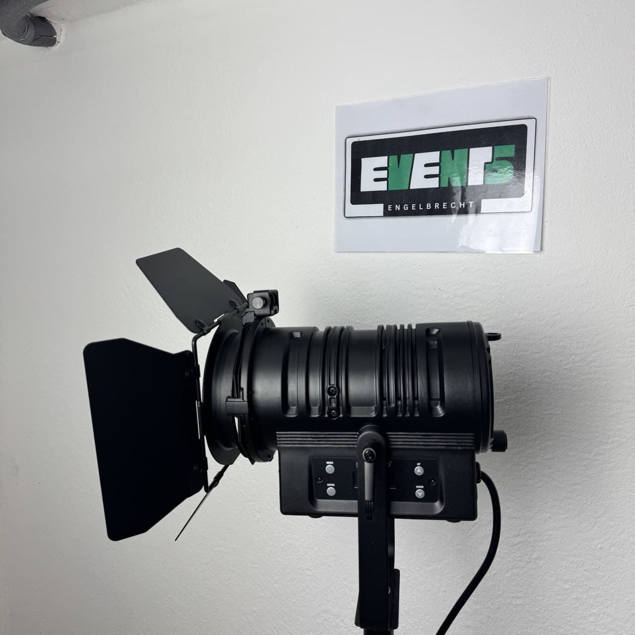 chwarzes Bühnenlicht mit Scheunentoren auf einem Ständer, positioniert unter einem Schild mit der Aufschrift „EVENTS ENGELBRECHT“ an einer weißen Wand.